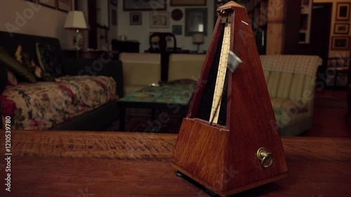 Metronome working on a table with blurred paintings on background