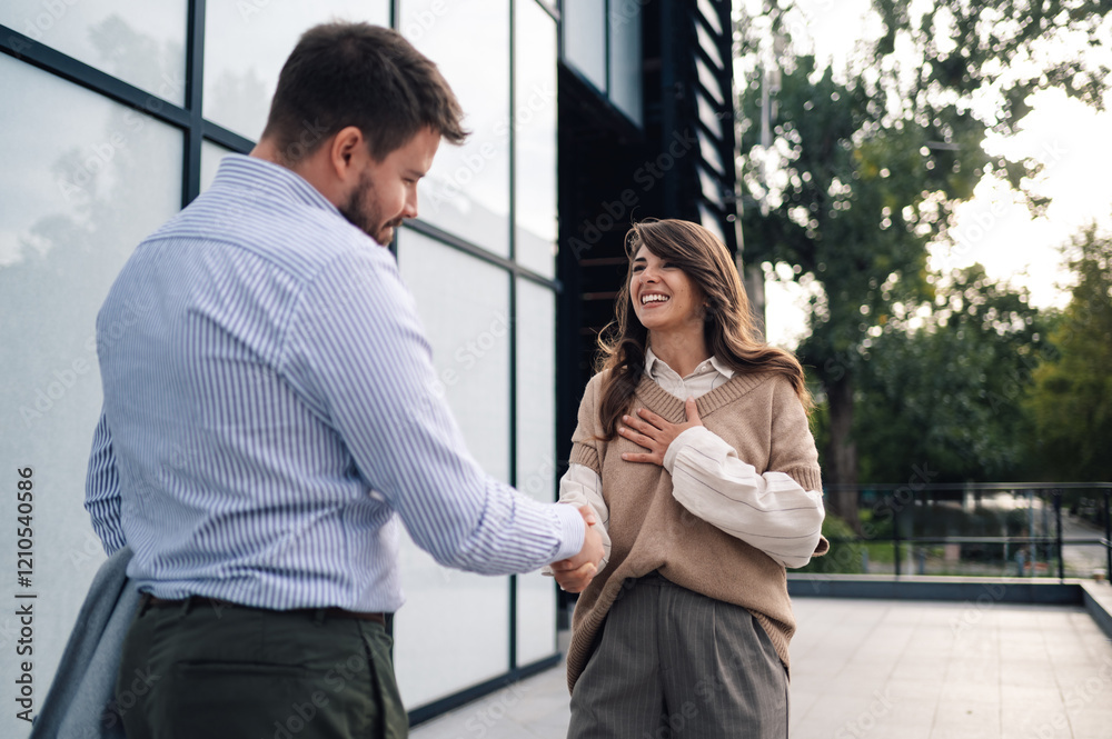 Business people shaking hands while smiling outside office building