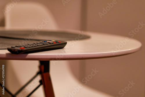 The TV remote control is forgotten on the white table.