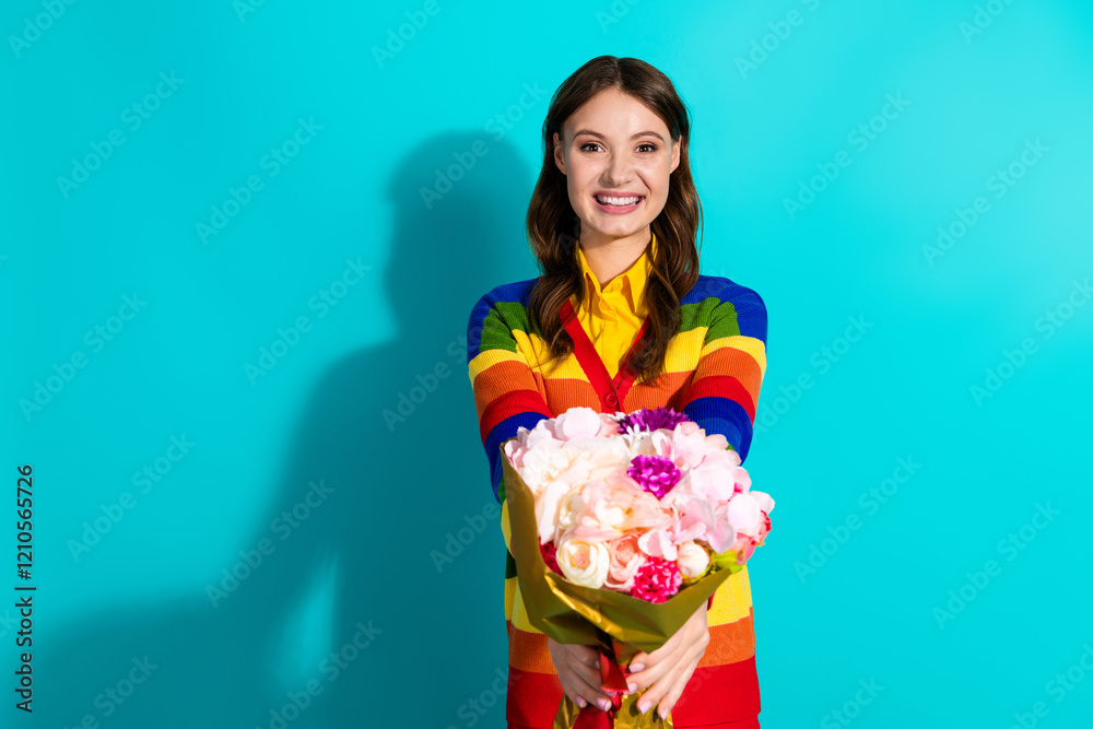Smiling young woman in colorful rainbow cardigan holding vibrant flower bouquet on teal background Smiling young woman in colorful rainbow cardigan holding vibrant flower bouquet on teal background