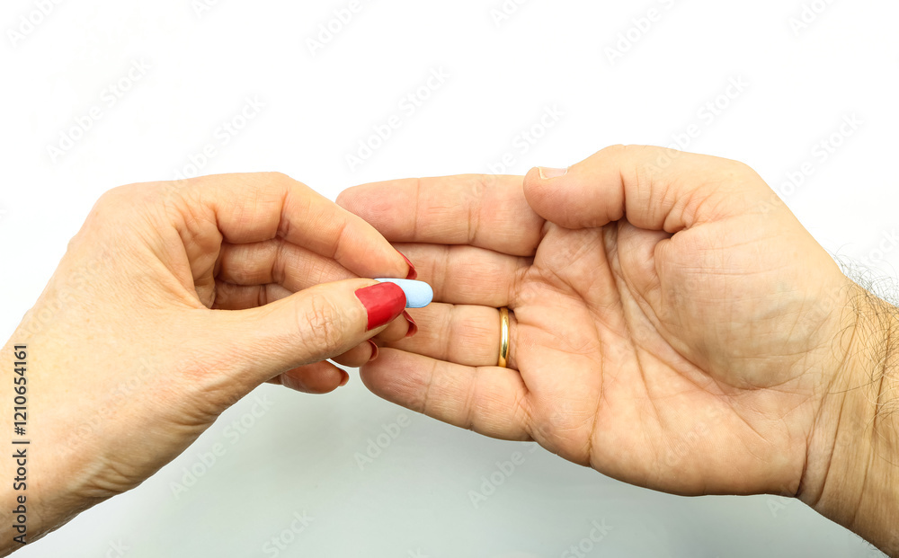 Woman's hand passing a blue pill to a man. Hormone, sterility treatment Woman's hand passing a blue pill to a man. Hormone, sterility treatment