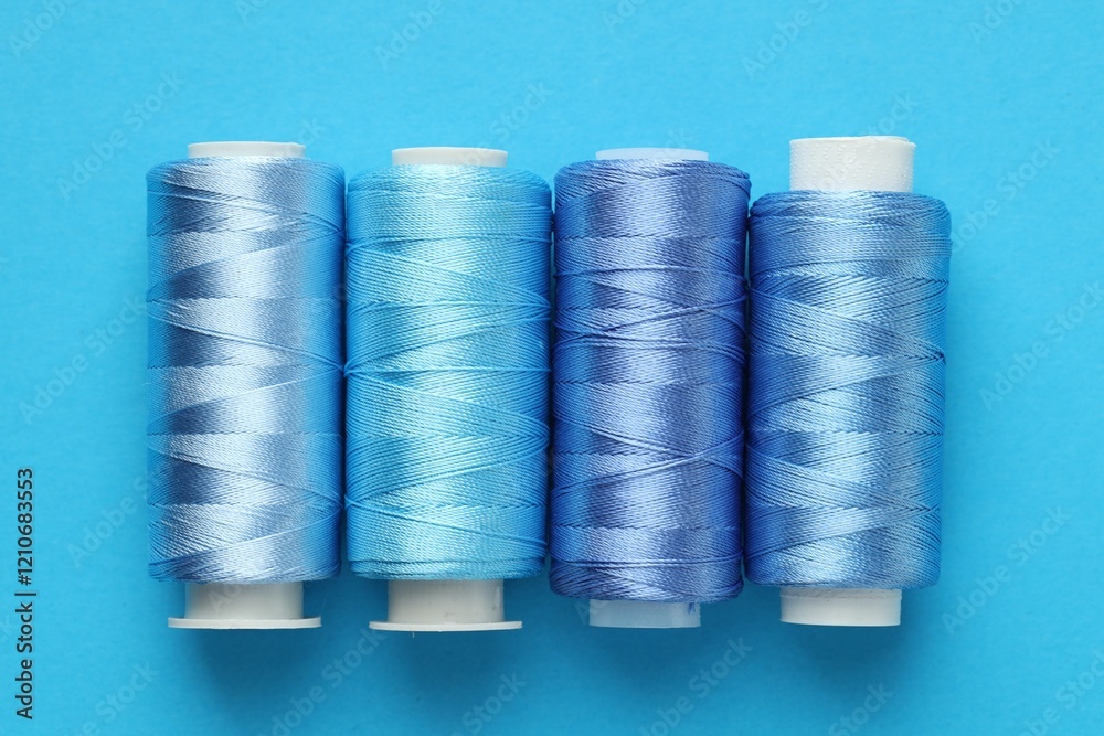 Spools of sewing threads on light blue background, flat lay Spools of sewing threads on light blue background, flat lay
