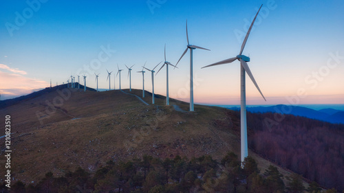 eolic generators spinning in a windy hill at sunset photo