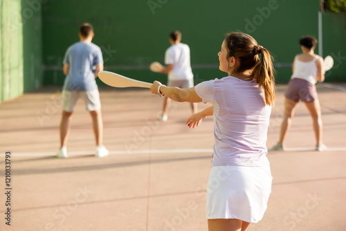 Active womans with enthusiasm playing paleta fronton group on the outdoor court photo