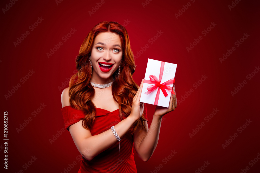 Photo of amazed girl hold showing christmas gift box package feel impressed on red color background Photo of amazed girl hold showing christmas gift box package feel impressed on red color background
