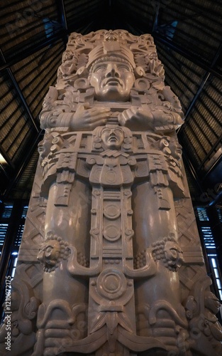 An impressive stone carving depicting an ancient deity with intricate details is showcased in a museum hall, illuminating the rich cultural heritage and artistry.