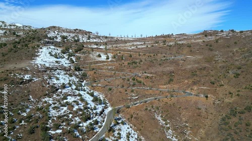 Aerial View of Serpentine Mountain Road with Snow-Dusted Hills