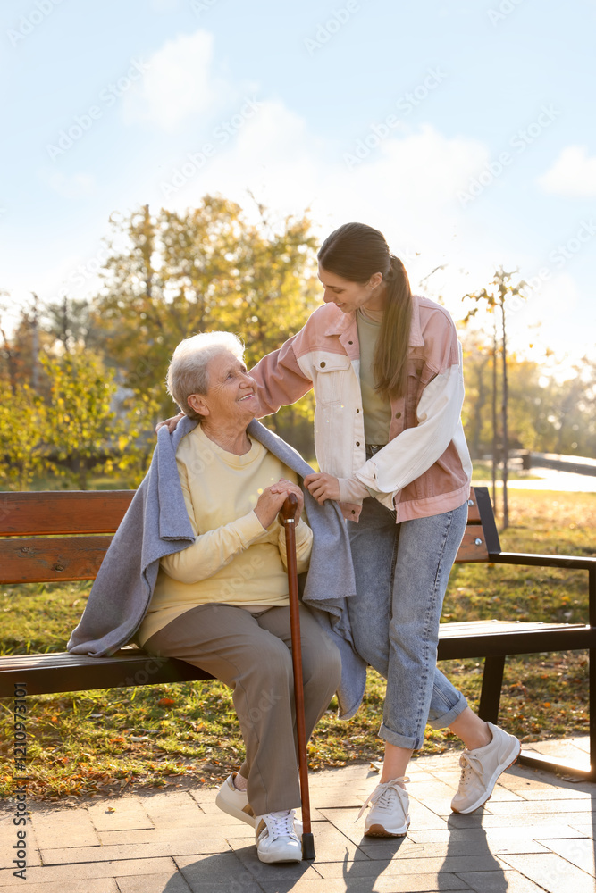 Elderly woman with walking cane and her caregiver in park Elderly woman with walking cane and her caregiver in park