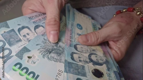 Hands Carefully Counting a Pile of 1000 Peso Bills