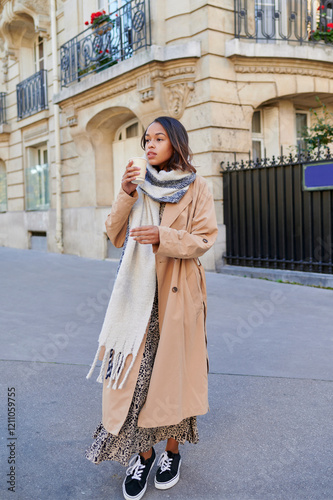 woman with raincoat and scarf in the street drinking coffee. photo