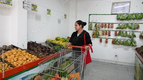 Woman Shopping for Fresh Fruits and Vegetables in a Grocery Store, Pushing a Market Cart and Walking Down the Aisle