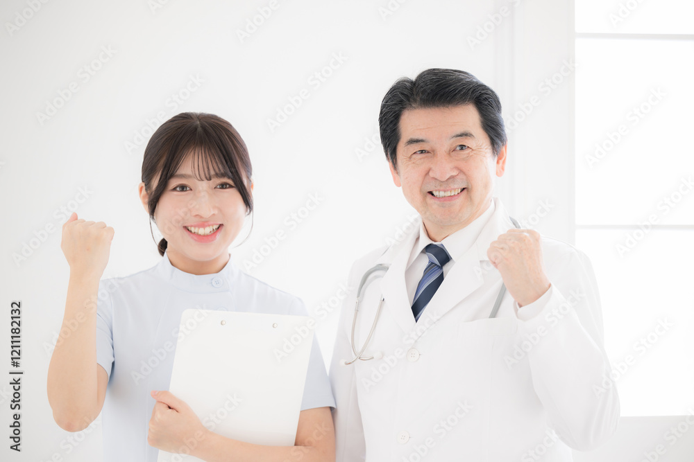 笑顔で立つベテラン医師と看護師のカメラ目線でガッツポーズ	