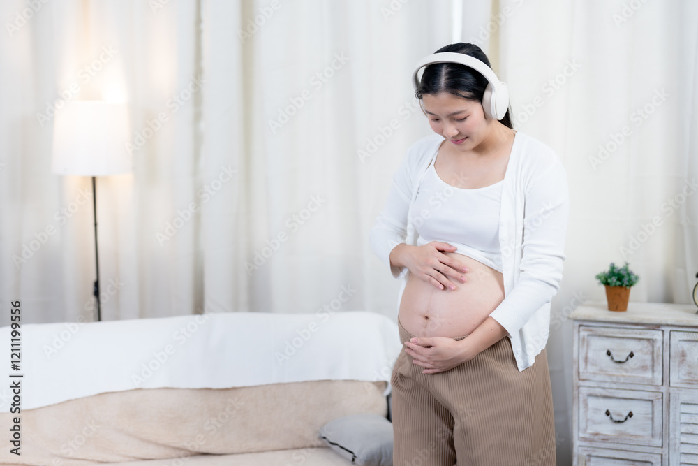 Close-up of an Asian pregnant belly with hands gently forming a heart shape in a cozy home. Symbolizes love, care, and a deep connection between mother and unborn child. Close-up of an Asian pregnant belly with hands gently forming a heart shape in a cozy home. Symbolizes love, care, and a deep connection between mother and unborn child.