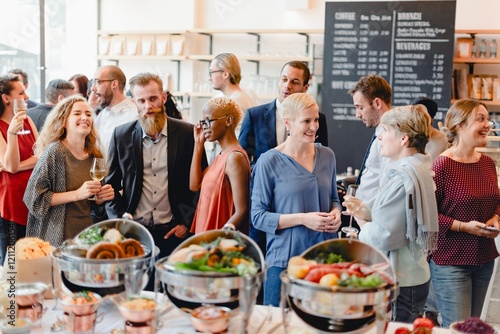 Professional people socializing at a gathering with food and drinks. Diverse crowd enjoying a business event at a social event with friends. Diverse professional people mingle at business event.