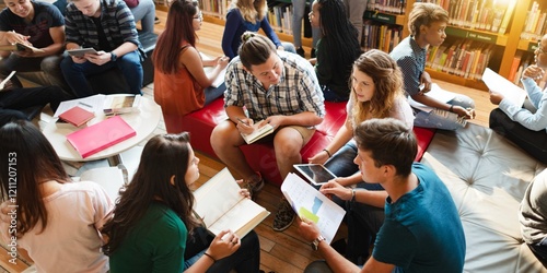 Diverse group of students study in library, read books, group discussion. Diverse group of students collaborative in school library. Diverse college students focus on books in groups in library