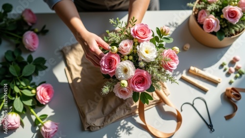 Florist girl making a bouquet in a flower shop. Top view of the florist's hands with flowers.