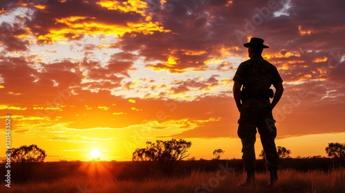 A sunset over the Australian outback with the silhouette of a soldier standing, representing the ANZAC spirit, emotional landscape photography with natural lighting 