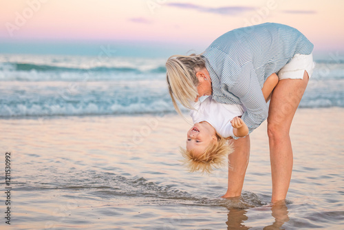 Mother holding toddler son upside down on Gold Coast beach