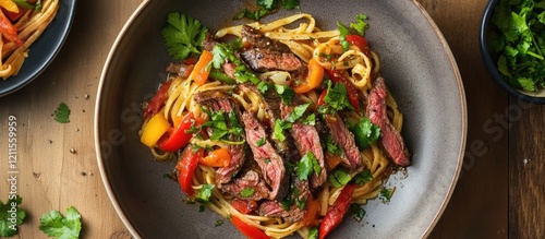 Vibrant beef trofie dish with colorful bell peppers and herbs in a grey bowl on a wooden table, showcasing inviting textures and delicious appeal.