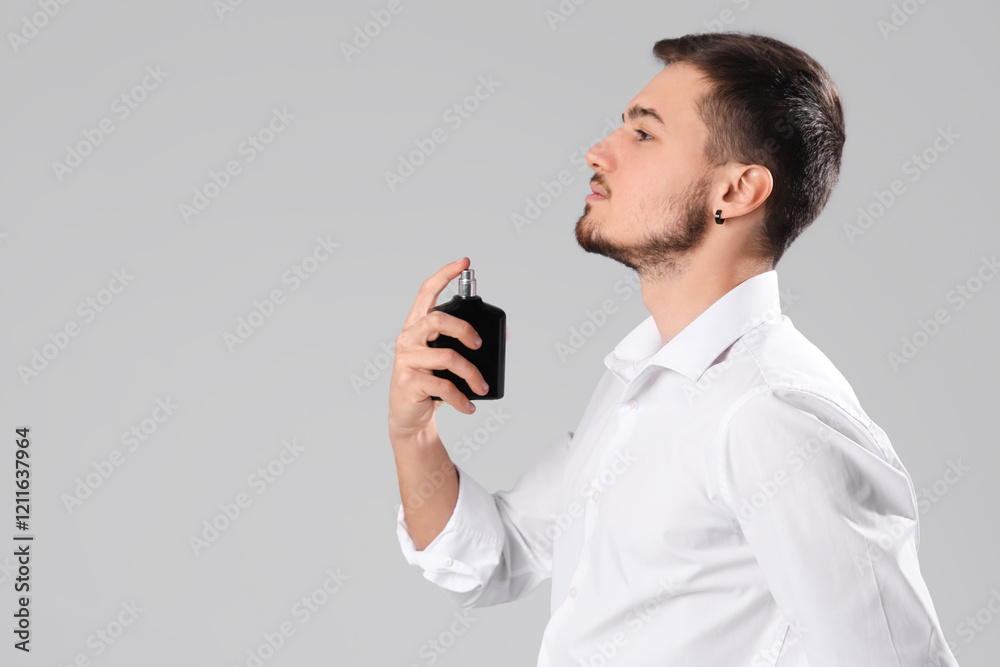 Handsome man applying perfume on light background Handsome man applying perfume on light background