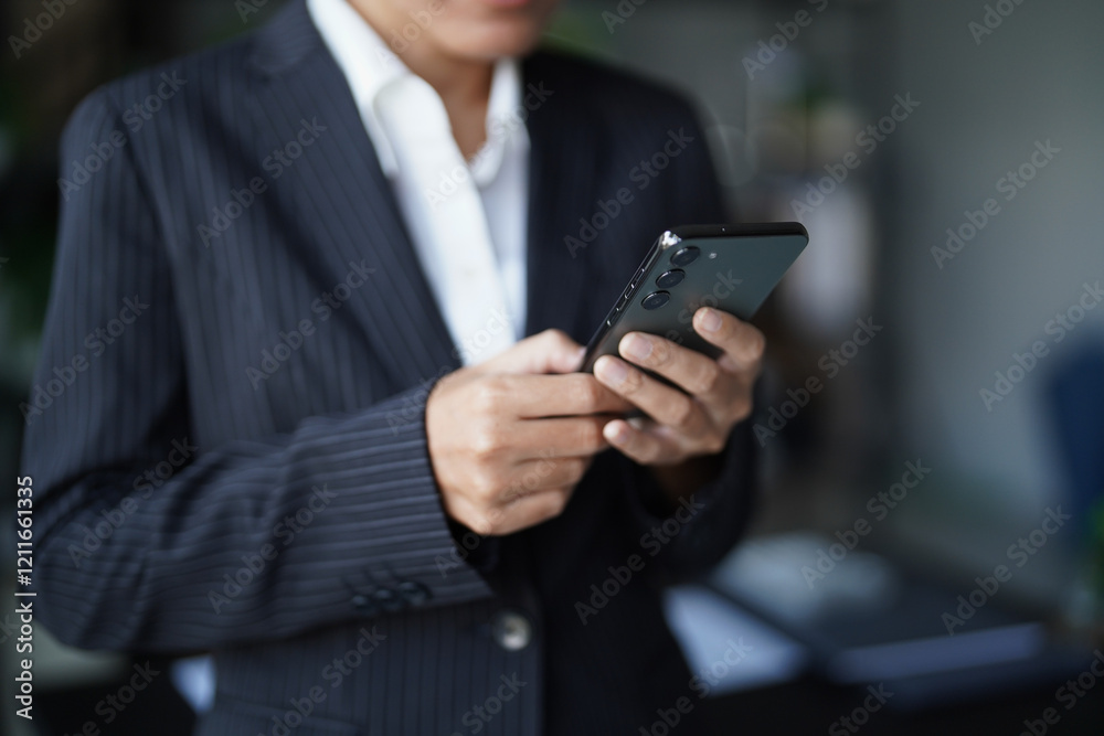 Asian businesswoman in suit standing using smartphone checking email Asian businesswoman in suit standing using smartphone checking email