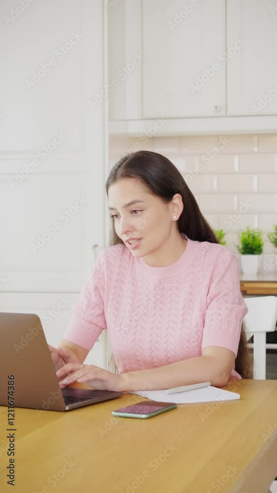 Beautiful young woman working with laptop computer in home kitchen. Work at home. Freelance, remote work Beautiful young woman working with laptop computer in home kitchen. Work at home. Freelance, remote work