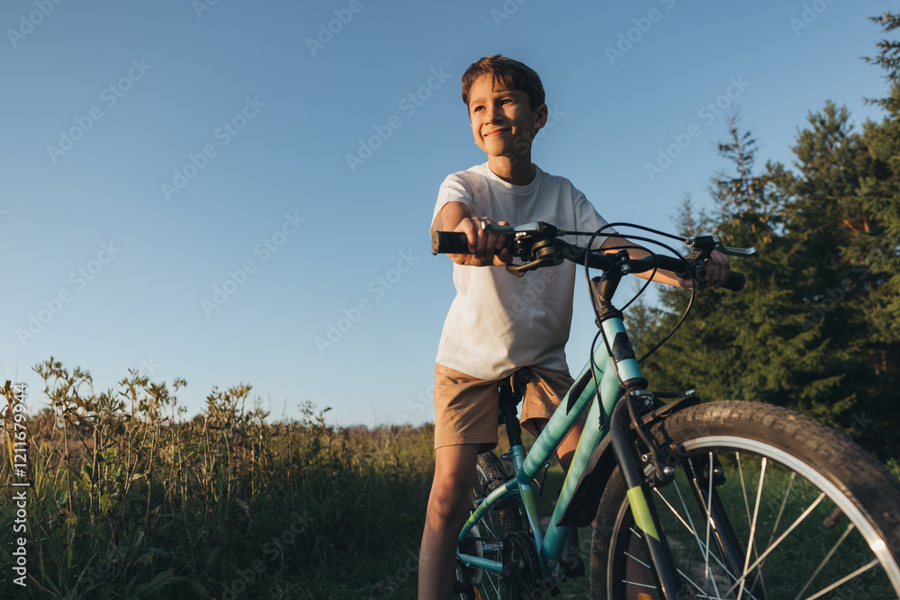 Boy riding a bicycle in a green field during sunset Boy riding a bicycle in a green field during sunset