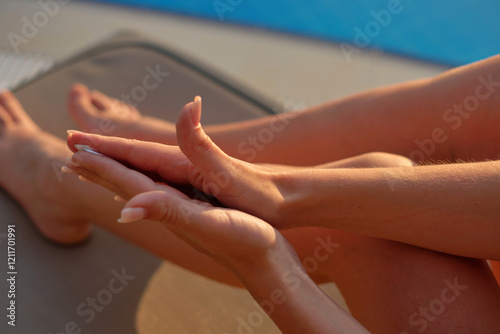 Wallpaper Mural Hands of a light-skinned woman with a nude manicure smear sunscreen on each other against the blue water of the pool. Young woman applying sunscreen lotion at swimming pool to take care of her skin. Torontodigital.ca