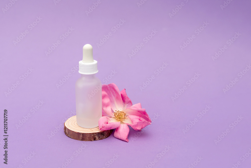 Cosmetic serum bottle with dropper lying on wooden slice with pink rose flower on purple background Cosmetic serum bottle with dropper lying on wooden slice with pink rose flower on purple background