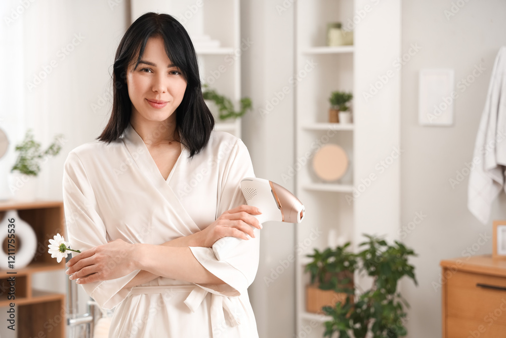 Beautiful young happy woman with modern photoepilator and flower in bathroom