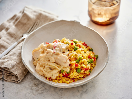 Creamy chicken with pasta topped with colorful vegetables is beautifully arranged in a bowl, creating a delightful meal. Soft lighting enhances the inviting presentation photo