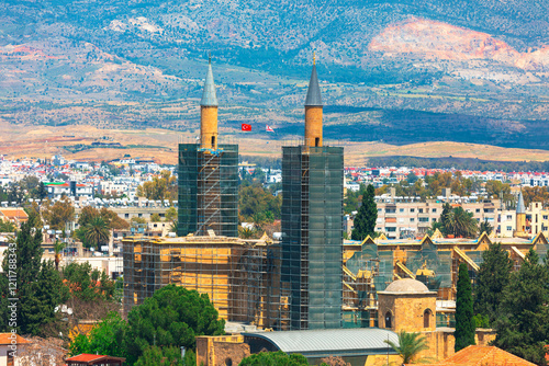 Obraz na płótnie Selimiye Mosque in Nicosia, Cyprus, stands amid urban and mountainous scenery, framed by twin minarets under renovation. Its striking Ottoman architecture reflects rich cultural history of the region w salonie