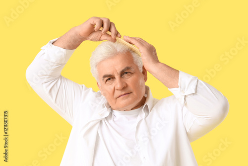 Senior man combing hair on ...