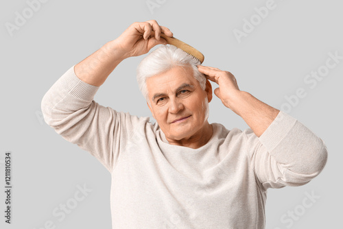 Senior man combing hair on ...