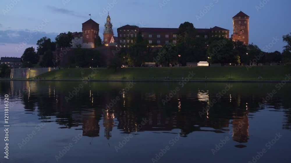 Wawel Castle illuminated at dusk over the Vistula River in Krakow, Poland, showcasing stunning reflections Wawel Castle illuminated at dusk over the Vistula River in Krakow, Poland, showcasing stunning reflections
