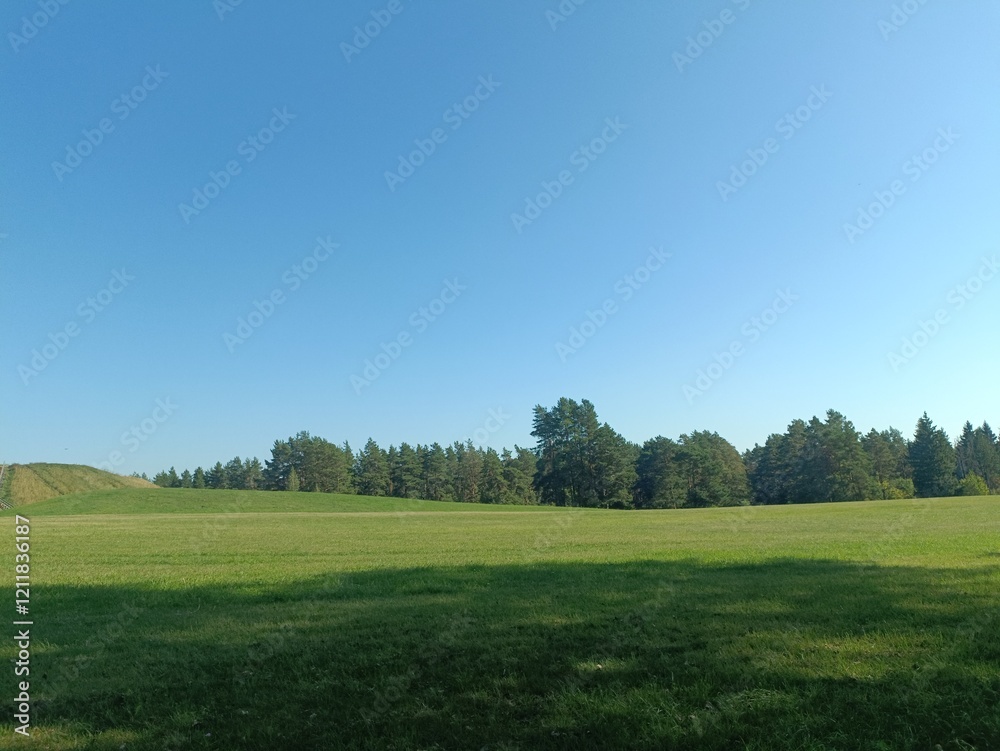 Salduve hill during sunny day. Small hill. Grass is growing on hill. Staircase leading to the top. Sunny day with white and gray clouds in sky. Nature. Salduves piliakalnis. Salduve hill during sunny day. Small hill. Grass is growing on hill. Staircase leading to the top. Sunny day with white and gray clouds in sky. Nature. Salduves piliakalnis.