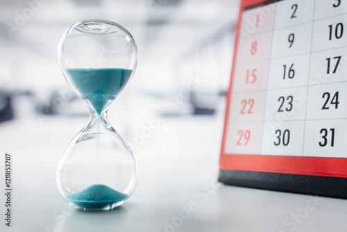 Hourglass and calendar on office desk important appointment date, schedule and deadline