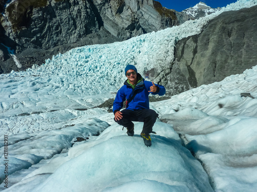 Hiker man on icy expanse of Franz Josef Glacier, Westland Tai Poutini National Park, New Zealand. Jagged ice formations, deep crevasses, snow-capped peaks. Unforgettable adventure on frozen landscape photo