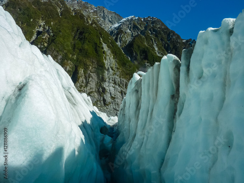 Deep crevasse cuts through ice of Franz Josef Glacier, Westland Tai Poutini National Park, South Island, New Zealand. Towering walls of ice, tinted blue, create dramatic natural sculpture. Extreme photo