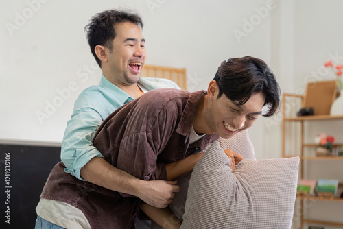 Joyful gay couple playing while moving into their new house, embracing and laughing together photo