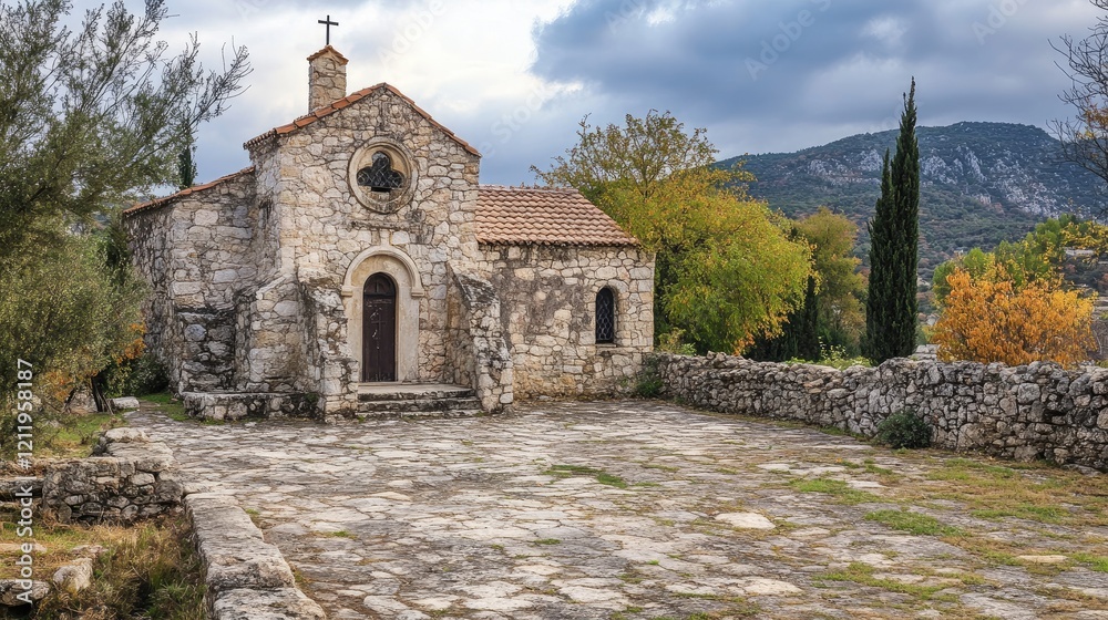 Fototapeta premium Historic stone church of Saint Athanasios in a picturesque village surrounded by nature and mountains on a cloudy day