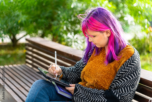 Young designer drawing on tablet in park: body positive, autism awareness