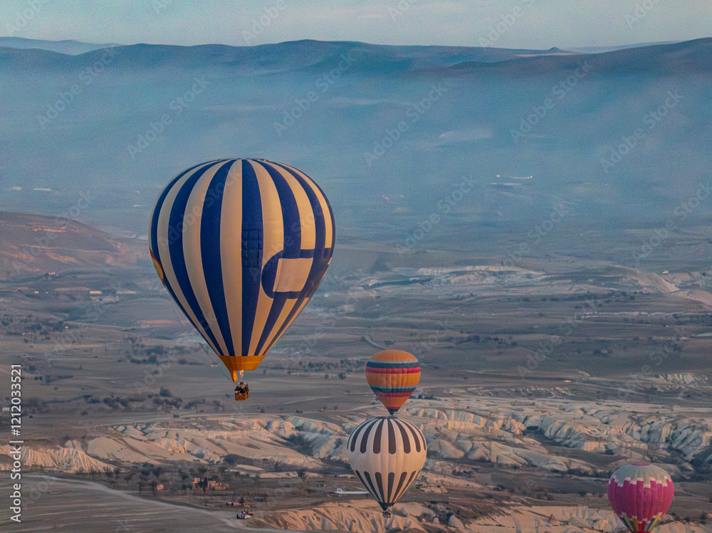 Close up aerial view of a hot air balloon floating above Love Valley with towering rock formations and other balloons in the background in Cappadocia
