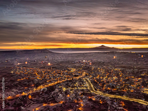 Obraz na płótnie Aerial drone view of Göreme with lights on at dusk during sunrise, with hot air balloons preparing for takeoff illuminated by burners w salonie