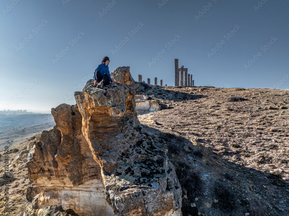 woman Hiker on Dramatic Overhanging Rock in Remote Wilderness in time and space sculpture park in cappadocia
