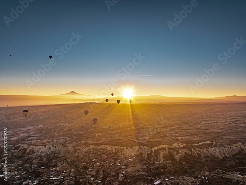 Obraz na płótnie Aerial view from above of the sunrise illuminating hot air balloons taking off near Göreme, casting long shadows over the valley in Cappadocia w salonie