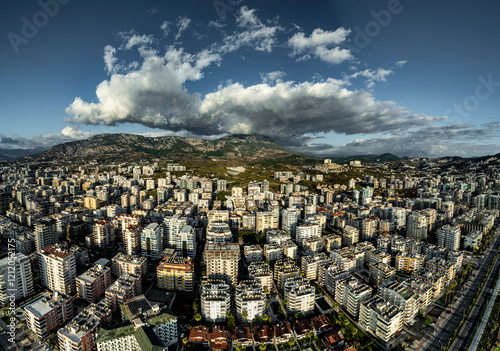 Aerial view of Mahmutlar district in Alanya with numerous high rise buildings by the sea and a mountain shrouded in clouds in the background photo