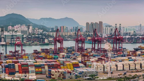 HONG KONG, CHINA - JANUARY 11, 2025: Containers stacked at bustling harbor with cranes operating in the background of the city skyline