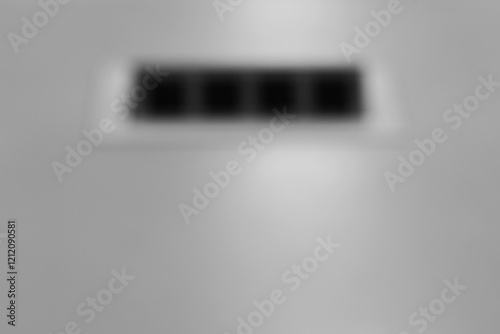 A dreamy view of a four squared grid grill on a commercial wall in black and white.