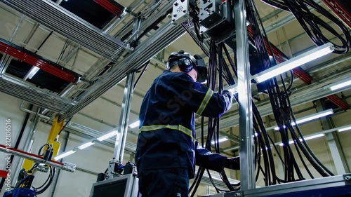 Worker engaged in electrical assembly tasks at industrial facility in the afternoon